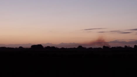 Sonnenuntergang-Auf-Dem-Feld-In-Neuseeland-Mit-Rauch,-Der-Aus-Dem-Familienhäuschen-Kommt