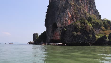 un barco se mueve más allá de un gran acantilado de piedra caliza