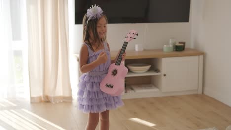 a beautiful little girl is playing the ukulele in the living room for her mom.