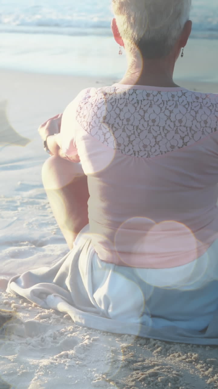 animación de puntos de luz sobre una mujer caucásica mayor practicando yoga en la playa y meditando