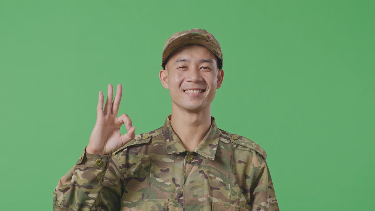 Close Up Of Asian Man Soldier Smiling And Showing Okay Gesture To Camera While Standing In The Green Screen Background Studio