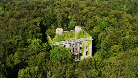 aerial orbit of moore hall ruins hidden in mayo forest on a sunny day