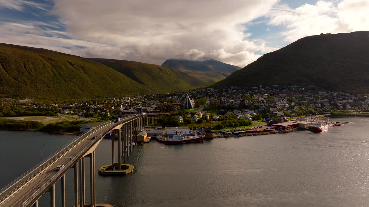 Cars drive over Tromso Bridge with views of Arctic Cathedral in the city