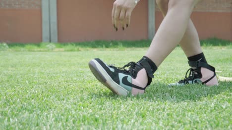 close-up of a woman stretching her legs while standing on a soccer field, warming up before exercise.
