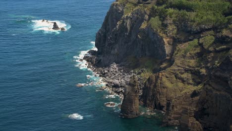 Olas-Golpeando-La-Costa-Del-Pueblo-De-Mosterios-Y-Un-Pájaro-Volando,-Isla-De-San-Miguel,-Azores,-Portugal