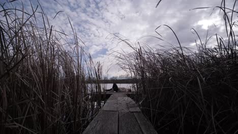 young man lies alone on wooden footbridge and staring at lake. thinking about life. peaceful atmosphere in nature. enjoying fresh air. back view.