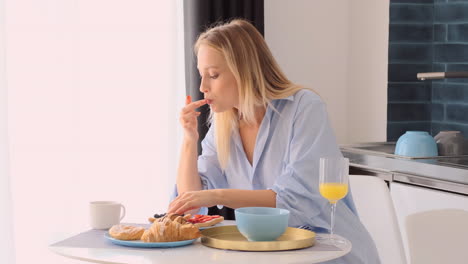 una mujer rubia desayunando en casa.