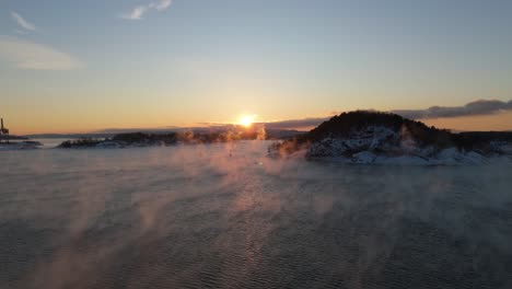 Golden-Hour-Sunset-On-Horizon-Near-Bjorvika,-Oslo-With-Fog-Floating-Above-Water