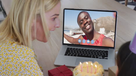 madre y hija caucásicas celebrando su cumpleaños mientras hacen una videollamada en una computadora portátil en casa