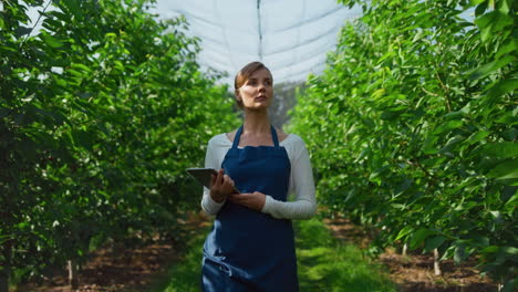 woman agronomist checking production with tablet on in green eco farm concept