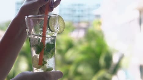 chica agita mojito congelado con paja de plástico en vidrio alto