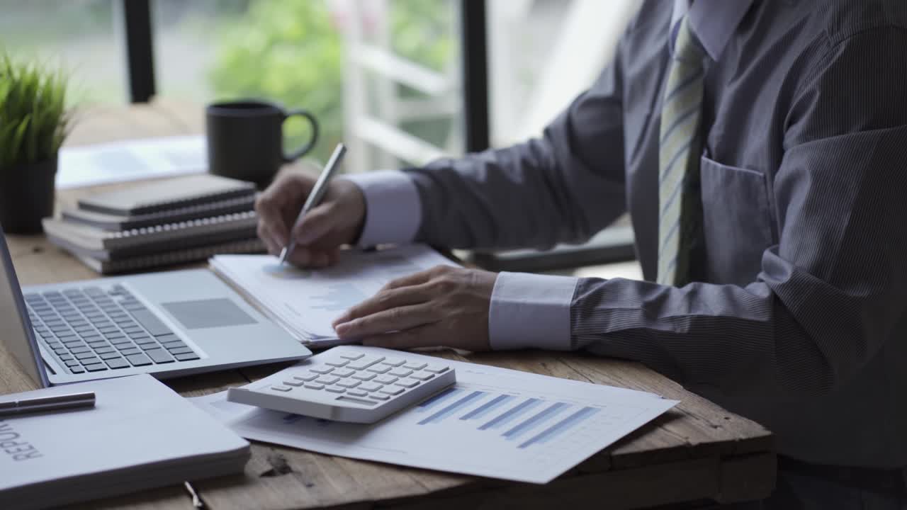 Businessman developing business project and analyzing marketing graph data with accounting documents and financial reports on 4k video table.