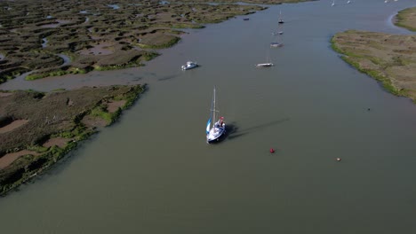 Velero-En-El-Río-Blackwater-Por-Marismas-Pantanosas-De-Tollesbury-Marina,-Essex,-Reino-Unido---Antena