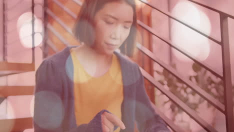 using tablet on staircase, woman surrounded by bokeh light animation