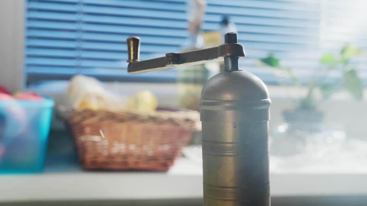 Un plano panorámico muestra un molinillo de café manual vintage iluminado por una suave luz matutina en la cocina. Es una escena de estilo de vida tranquila, ideal para marcas de café, cafeterías y rituales diarios en el hogar.