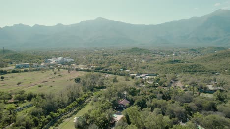 Aerial-over-suburbs-residential-area-and-revealing-mountain-landscape-in-distance,-sunshine-daytime-capture,-location-Santiago---municipality-in-Mexico