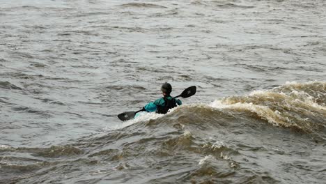 river surfing kayaker rides the swell of a wave on the ottawa river