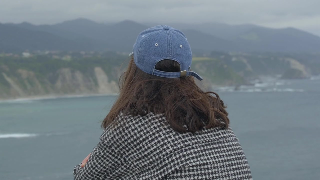 Woman looking at the ocean from a high coastal cliff