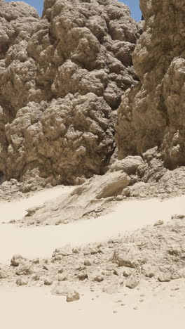 a view of a desert canyon with towering rock cliffs and white sand