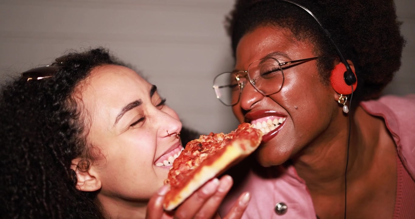 Two Happy Diverse Friends Sharing Pizza and Laughing