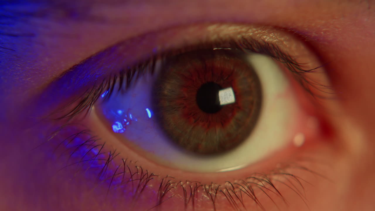 Primissimo piano di un occhio umano con riflesso di luce blu