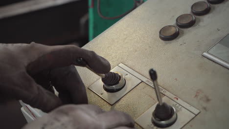 factory worker operating industrial machinery with joystick controls, closeup