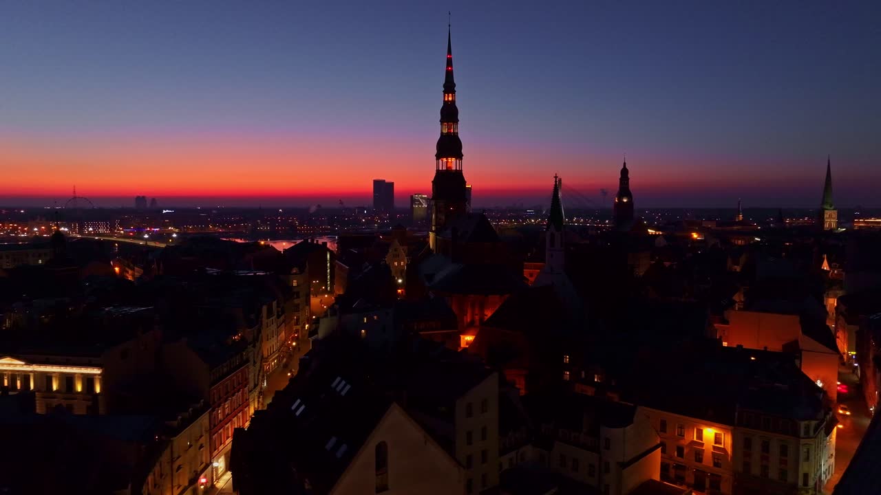 Riga Old Town historic skyline glows at twilight as sun fades beyond the horizon