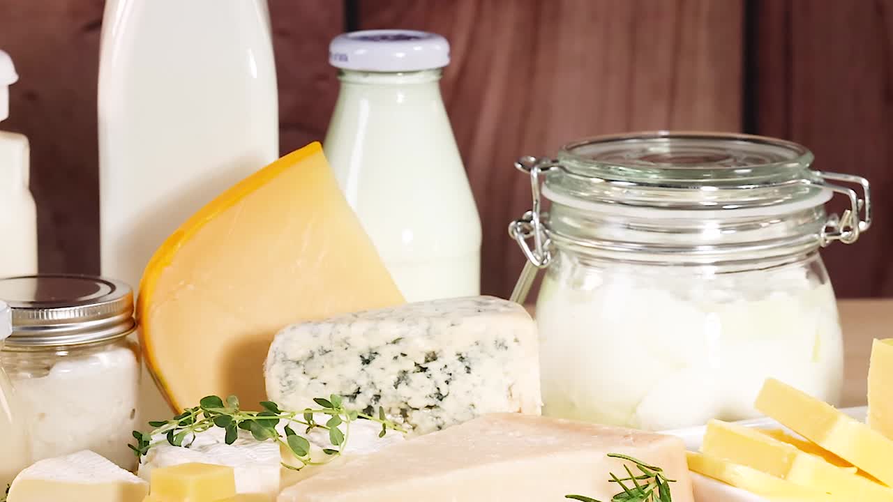 A variety of dairy products including cheese, milk, and yogurt displayed on a wooden surface.