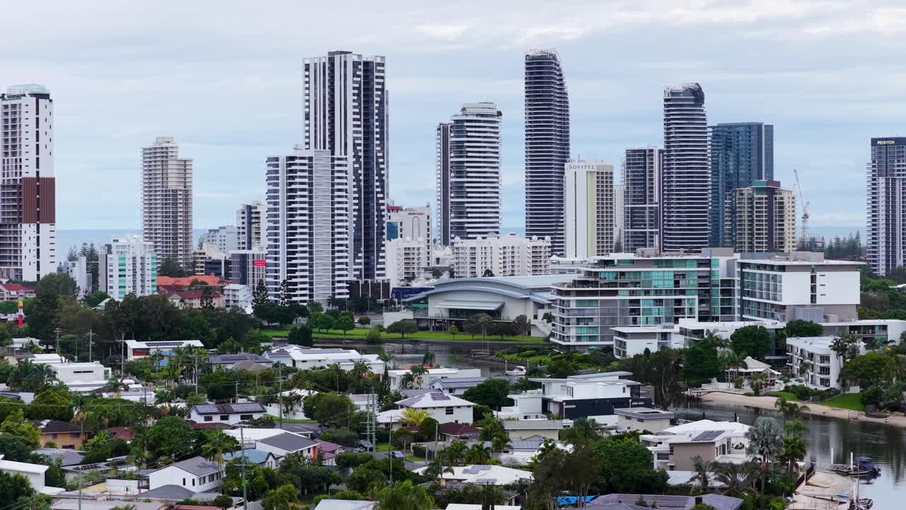 Aerial view of Gold Coast's urban skyline with high-rise buildings and waterways under cloudy skies