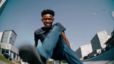 joyful young black man kicking and smiling in urban setting