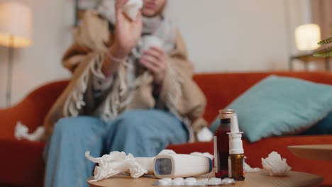 sick cold woman suffering from cold or allergy at home in living room blows nose snot into napkin