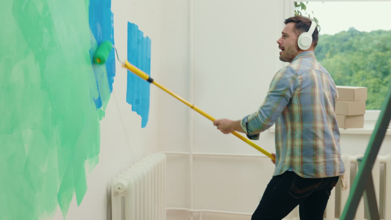 Man Painting a Wall While Dancing to Music