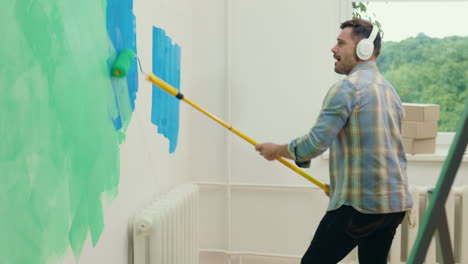 man painting a wall while dancing to music