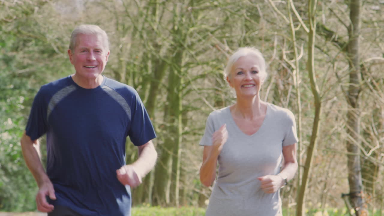 Senior Couple Running In Countryside Exercising During Covid 19 Lockdown