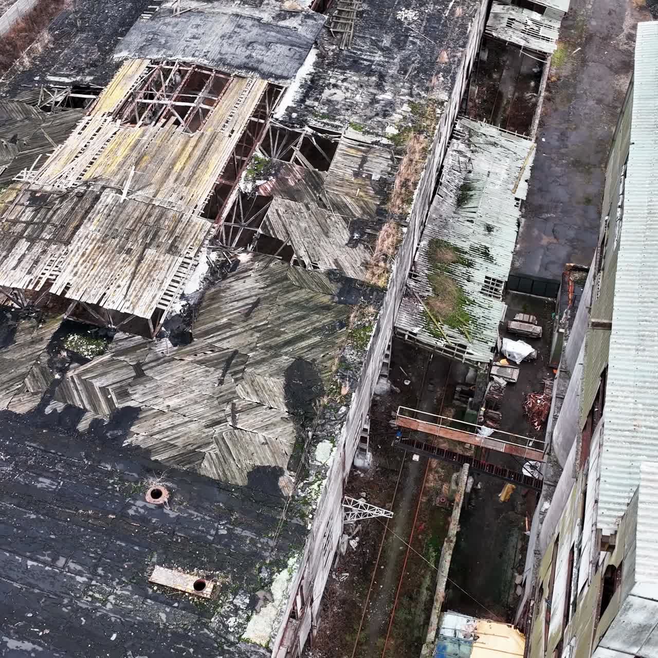 Holes in the roof of a warehouse in old abandoned chemical plant. Territory and buildings in decay. Aerial perspective