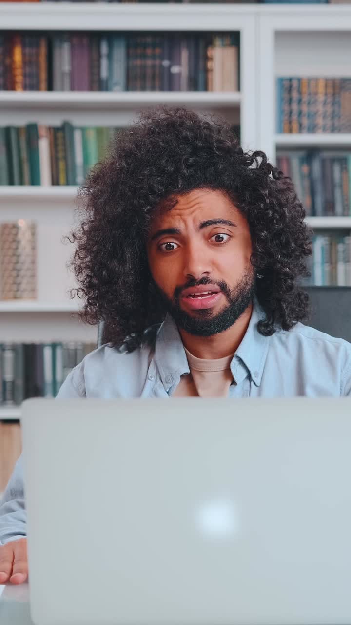 Young irritated arabian man participates in video meeting sits in office at desk