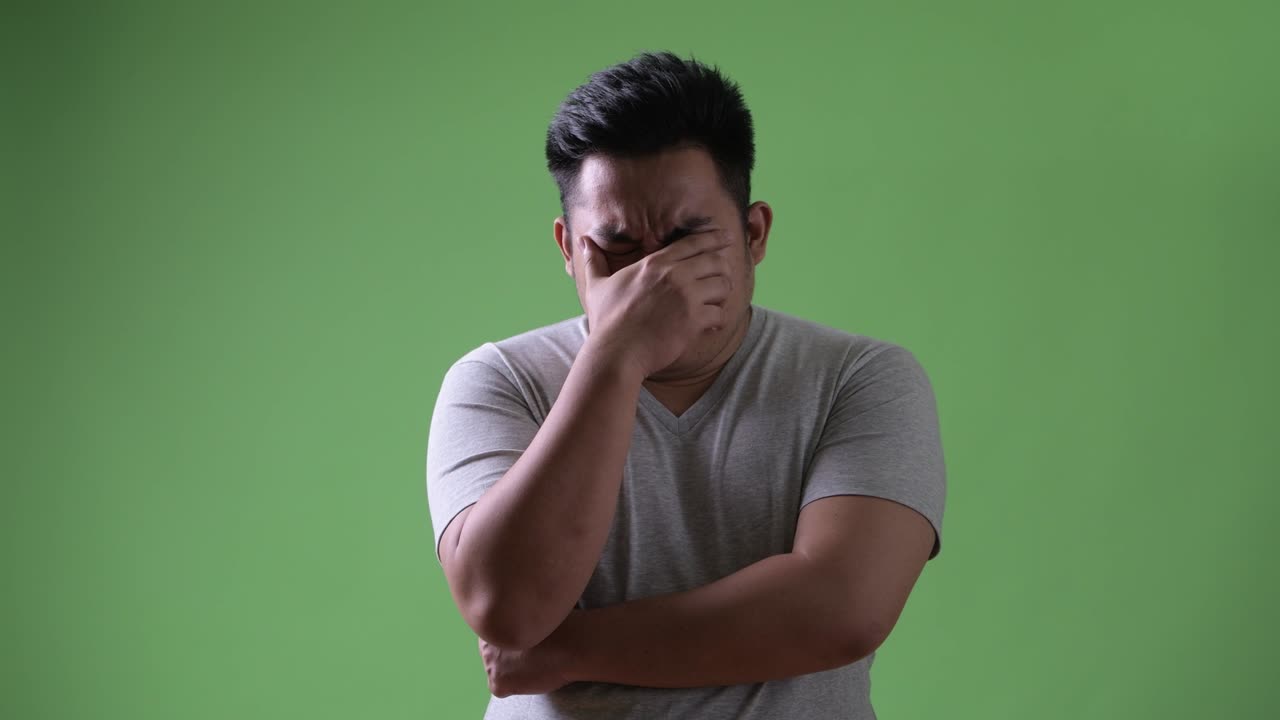 초록색 배경에 젊은 잘생긴 과체중 아시아인