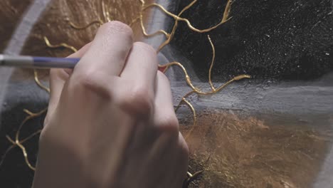 man hand paints an abstract, textured picture with acrylic paints. close up shot