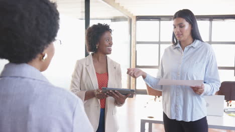 presenting ideas, businesswoman holding paper while colleague listening attentively with tablet
