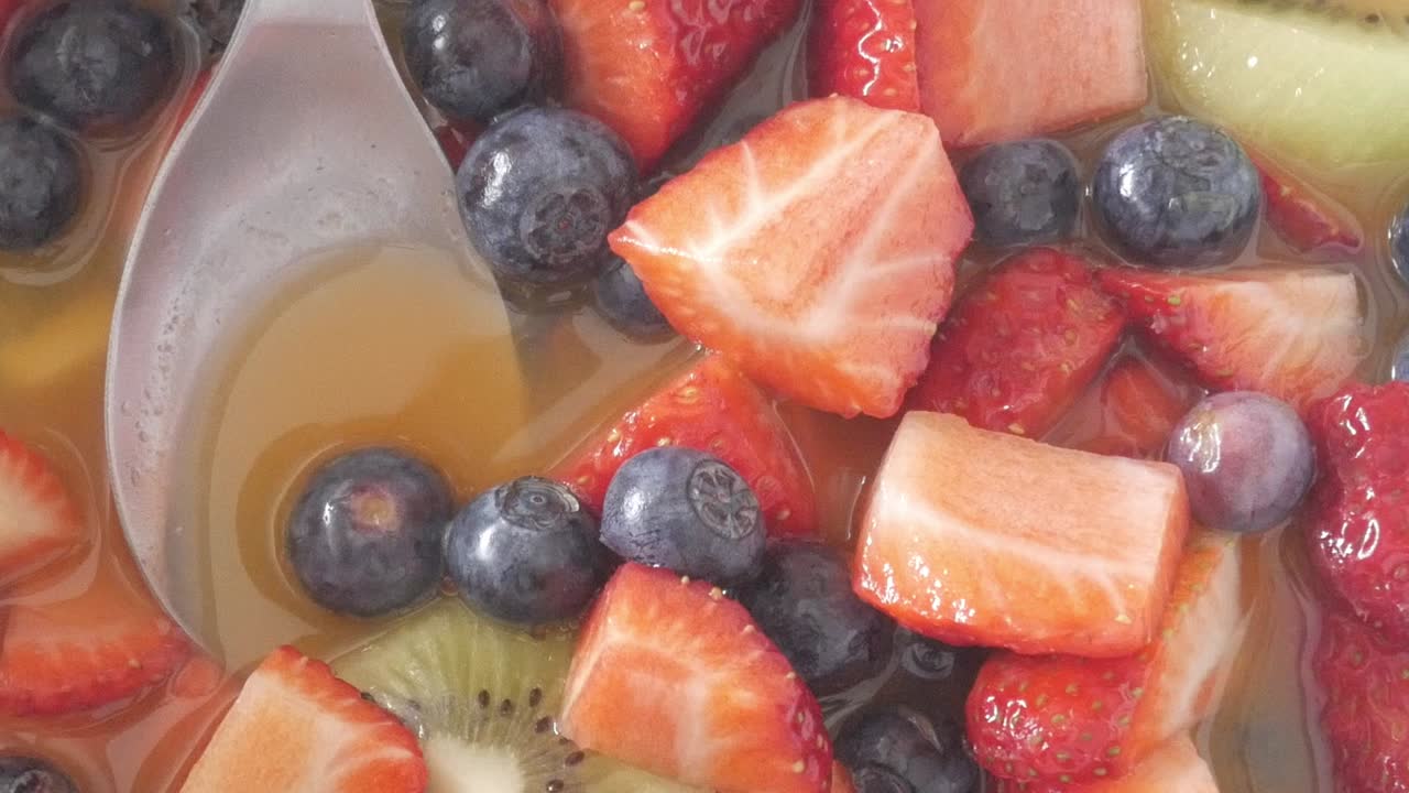 Естественный свет подчеркивает сочный фруктовый салат с клубникой, черникой и киви во время панорамирования вправо.