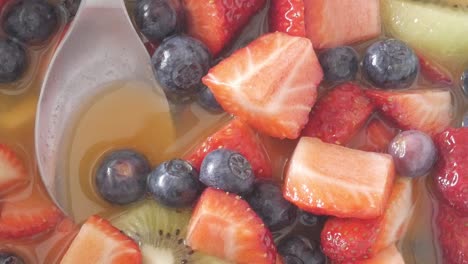natural light highlights juicy fruit salad with strawberries, blueberries and kiwi during pan right movement