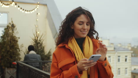 woman using phone and enjoying view from rooftop terrace