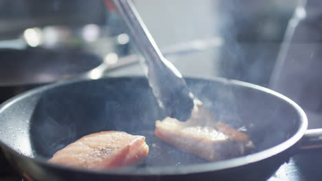 turning fish fillet with tongues on skillet