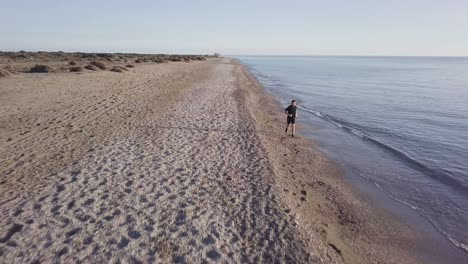 young runner man training on beautiful sunset at beach. drone view
