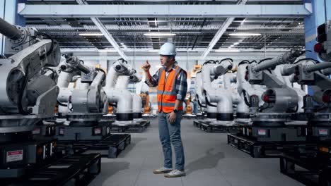 Engineer interacting with robotic arms in a factory