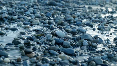 Mesmerizing-water-gracefully-flowing-over-rocks-along-the-serene-lake-shore,-a-tranquil-display-of-nature's-beauty