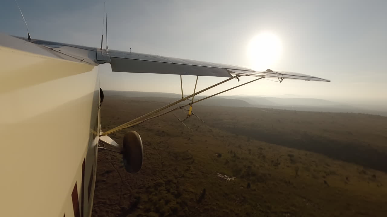 Seitenansicht eines kleinen Flugzeugs über Sträuchern an einem sonnigen Morgen.