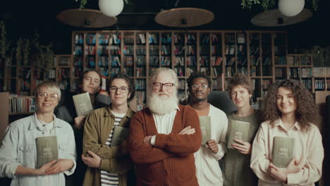 retrato grupal de autor sénior y jóvenes lectores con libros en la biblioteca