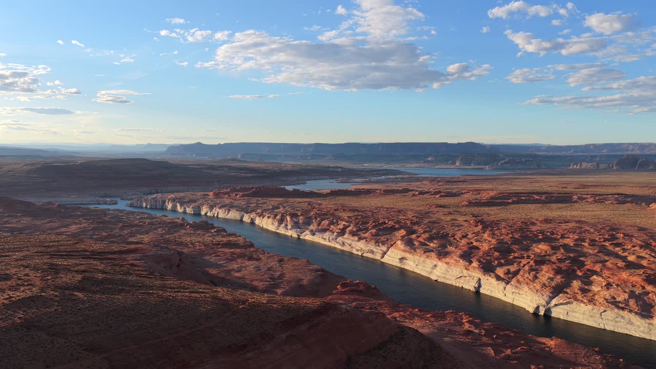 Una ripresa cinematografica con drone cattura il maestoso fiume Colorado che serpeggia tra scogliere di arenaria rossa e il Lago Powell. Questo vasto paesaggio desertico è ideale per il turismo del Sud-Ovest e i media di viaggio.