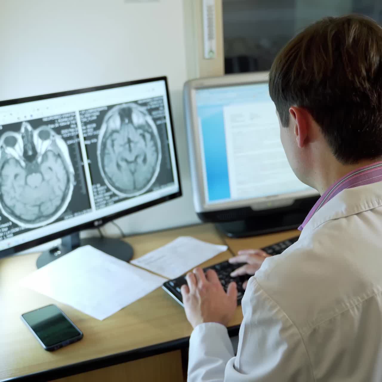 Doctor Looking Scans Results. Doctor looking at patient scans on computer screens in modern clinic